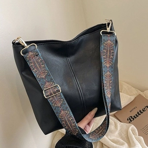 Black leather tote bag with colorful ethnic woven strap and golden hardware accents