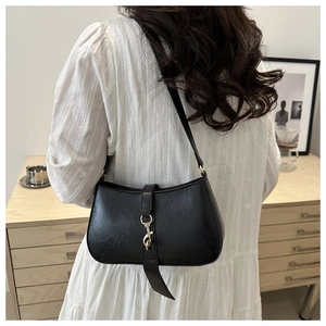 Detalle de bolso de hombro negro de cuero PU con broche dorado sobre vestido blanco