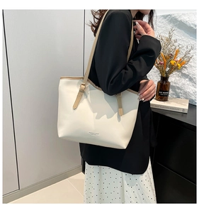 Close-up of beige tote bag with slim brown straps and fashion text on leather