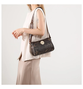 Detail of vintage printed crossbody barrel bag with wide woven strap and gold metal logo