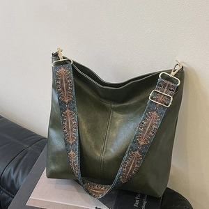 Detail of dark green PU leather tote bag with lychee texture and ethnic patterned strap