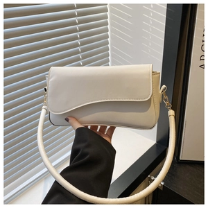 Detalle del bolso minimalista en cuero crema con solapa asimétrica y correa ancha