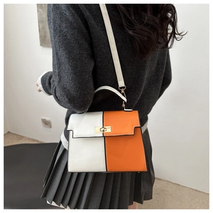 Detalle del bolso trapezoidal bicolor con cierre dorado y correa blanca ajustable