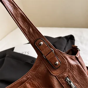 Primer plano del bolso tote marrón vintage con textura de cuero y remaches metálicos de refuerzo