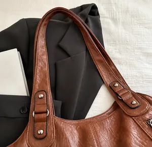 Detalle de bolso vintage marrón con textura de cuero granulado y remaches metálicos