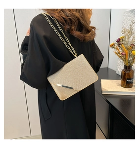 Detail of champagne gold glitter envelope bag with metallic bar and elegant chain strap