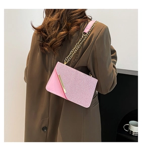 Side view of pink sequined crossbody bag with gold chain strap on a model