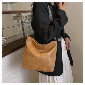 Detail of brown tote bag featuring vintage texture and colorful woven shoulder strap