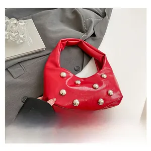 Detail of red crescent bag with silver rivets held against a grey blazer jacket
