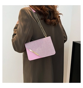Detailed macro view of pink glitter envelope bag with golden chain and metallic trim
