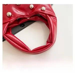 Detailed close-up of a red studded moon bag handle with glossy leather finish