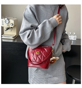 Détail du sac seau matelassé bordeaux avec fermoir doré et pendentif ours en peluche