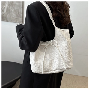 Détail du sac cabas blanc à texture crocodile avec un nœud décoratif élégant