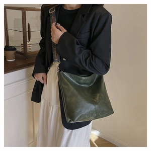 Detail of dark green tote bag featuring an ethnic pattern woven shoulder strap in a cafe