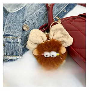 Vue détaillée d'un charme monstre en peluche marron avec nœud sur un sac à carreaux