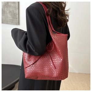 Détail du grand sac cabas tressé bordeaux avec texture cuir et lacets latéraux élégants