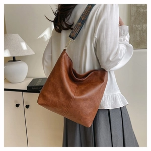 Detail of vintage brown leather tote bag featuring an embroidered ethnic wide strap
