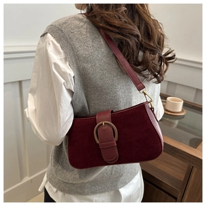 Détail du sac sous l'aisselle bordeaux avec boucle dorée et texture en cuir mat