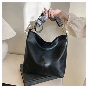 Detail of black leather tote bag with colorful ethnic pattern wide shoulder strap