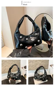 Detail of glossy black leather hobo bag with large silver spherical rivets and texture