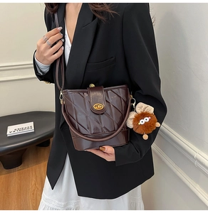 Détail d'un sac seau en cuir matelassé marron foncé avec fermoir doré et grigri