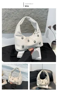 Detail of white leather hobo bag featuring decorative silver metal rivets and chic texture