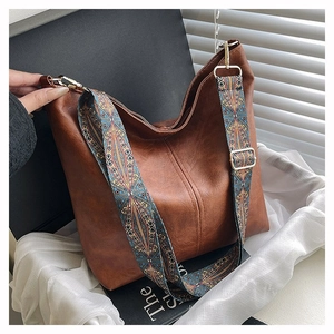 Close-up of brown suede hobo bag with a bohemian ethnic pattern wide shoulder strap