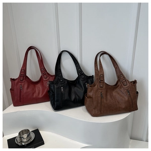Detalle de tres bolsos tote grandes de cuero en granate, negro y marrón con bolsillos laterales