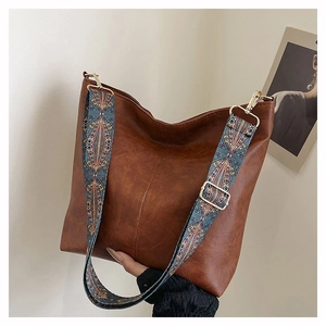 Detail of brown PU leather tote bag with a colorful geometric woven wide shoulder strap