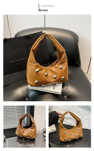 Detail of a brown crescent shoulder bag with silver rivet studs and glossy finish