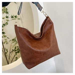 Detail of deep brown tote bag featuring a bohemian style wide colorful woven strap