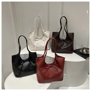 Détails de sacs cabas tressés en noir, blanc, marron et bordeaux avec nuds élégants