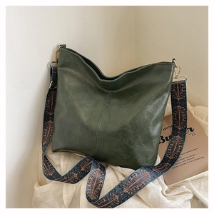 Close-up of dark green hobo bag featuring a wide ethnic style embroidered shoulder strap