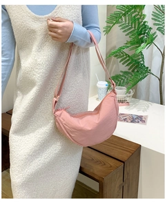 Detail view of pink nylon dumpling bag showing adjustable strap and zip closure on model