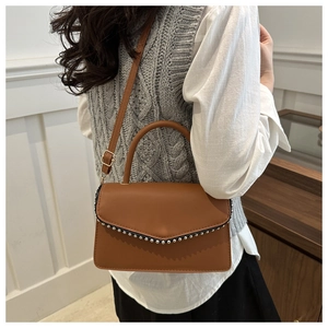 Detail showing the brown crossbody bag with silver bead trim and adjustable shoulder strap