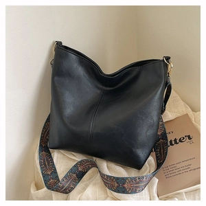 Detail of black faux leather tote with colorful geometric patterned wide strap and gold hardware
