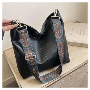 Detail of detachable ethnic print wide strap and gold hardware on black tote bag
