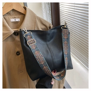 Detail of black tote bag featuring a colorful ethnic style woven wide shoulder strap