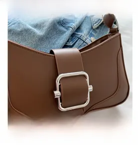 Close-up of brown leather bag with silver square buckle and clean stitching detail