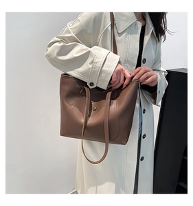 Détail d'un grand sac fourre-tout marron en simili cuir avec poche avant et bouton pression