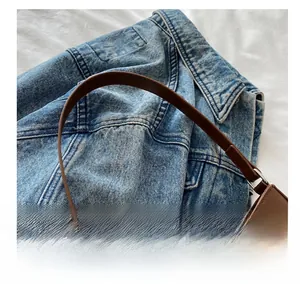 Detail of soft brown leather handle with silver buckle on a stylish baguette shoulder bag