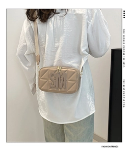 Beige gewatteerde cameratas met reliëf SM-logo en brede stoffen band op een model