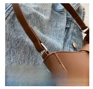 Detail view of the silver metal ring buckle and sturdy stitching on a brown leather handbag
