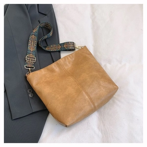 Detail of camel tote bag with ethnic pattern wide strap on grey blazer background