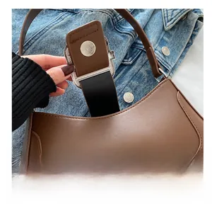 Close-up of silver magnetic clasp on brown leather shoulder bag against denim jacket