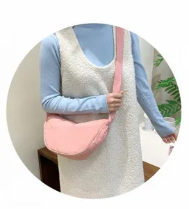 Detail of pink crescent crossbody bag showing textured nylon fabric and wide strap