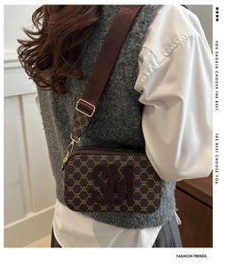 Detail of vintage brown camera bag with monogram pattern and wide adjustable shoulder strap