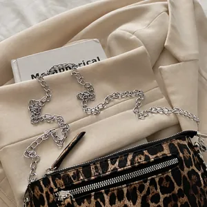 Detail shot of leopard print handbag with silver metal chain strap on minimalist background