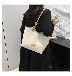 Detail of minimalist tote bag with contrast piping and knotted shoulder strap detail