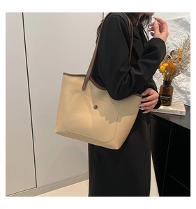 Détail du grand sac cabas beige avec bandoulière marron et bouton de poche avant